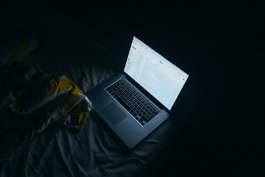 Laptop on a bed in the dark.