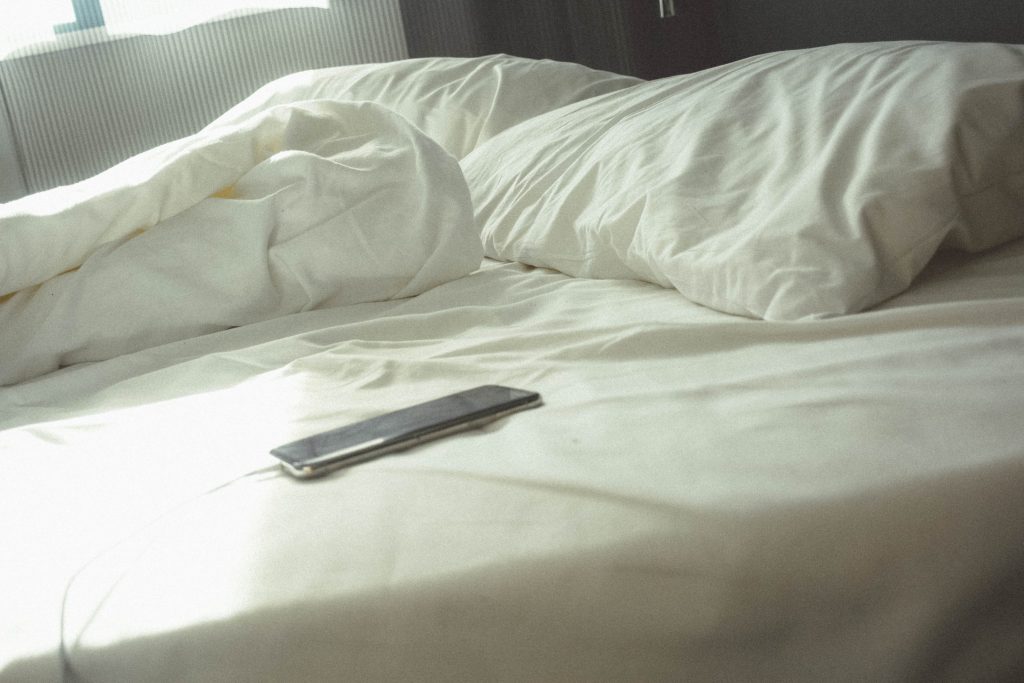 Mobile phone lying charging on a bed.