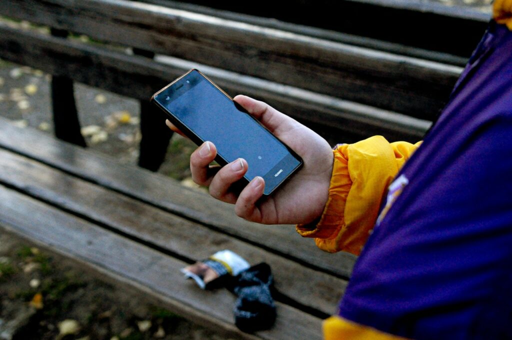 Person holding phone in front of a wooden bench