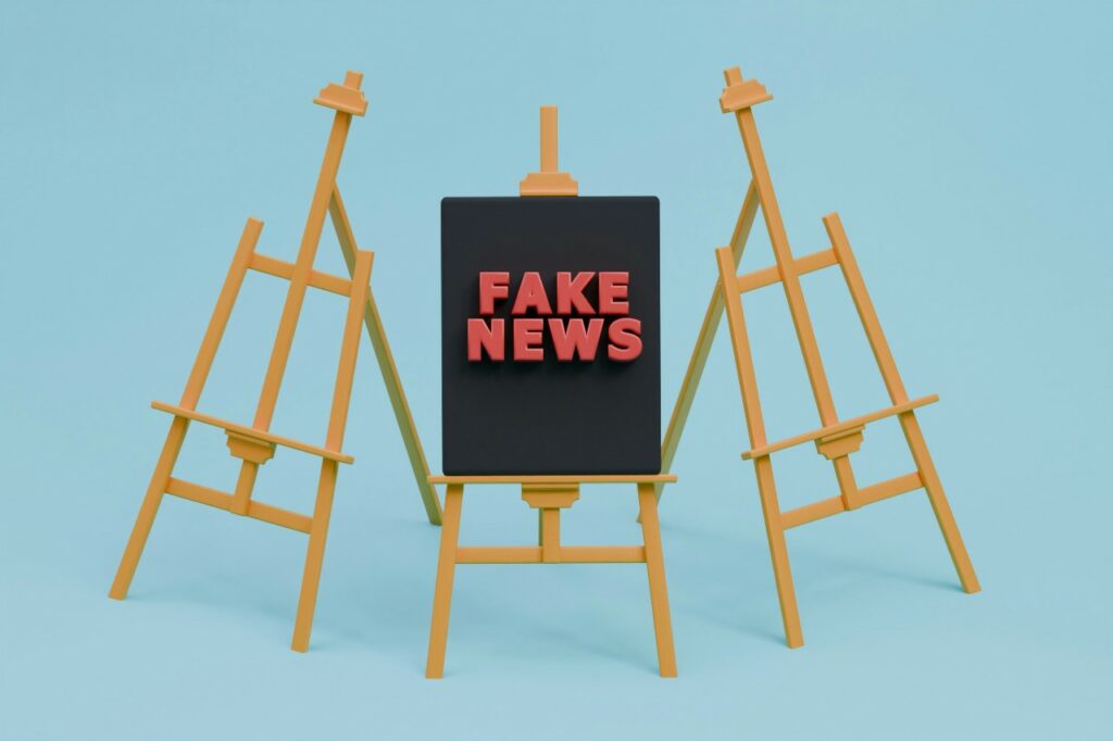 Three painting aisles side by side. Middle one has a black canvas on it with 'Fake News' in red letters.